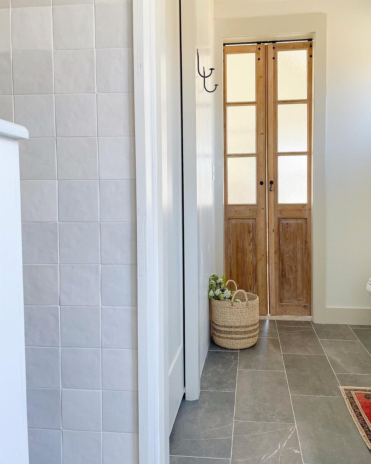 Tall wooden antique French doors with glass panes located at the end of a hallway.