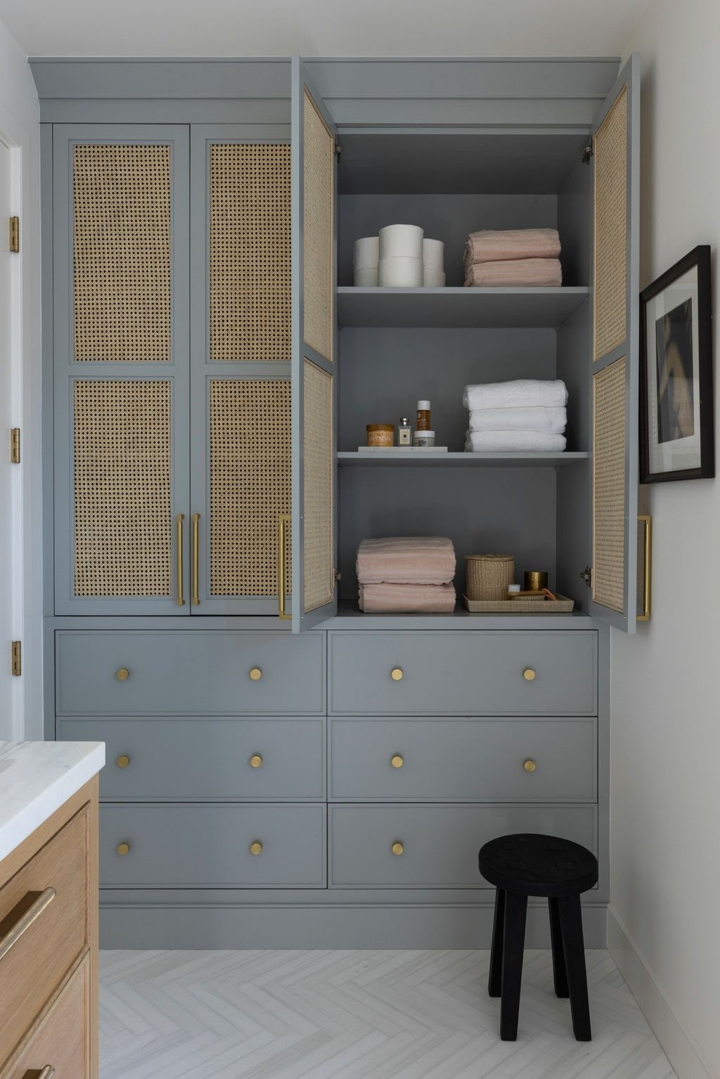 Tall light blue linen tower with open doors revealing organized towels and toiletries on shelves.