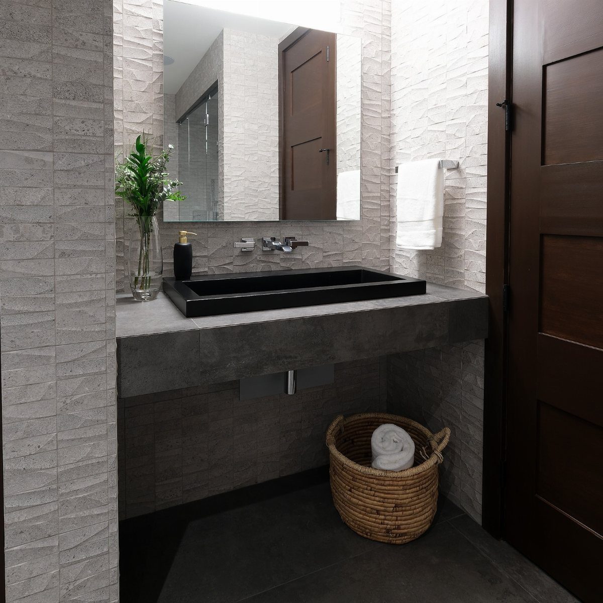 A dark grey concrete countertop with a black vessel sink in a modern bathroom.