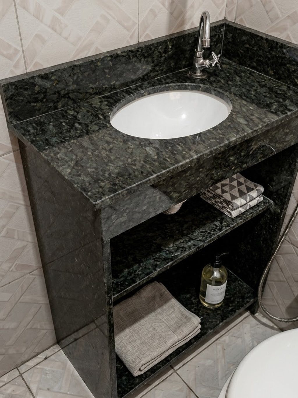 Dark green granite bathroom countertop with a white oval sink and chrome faucet.