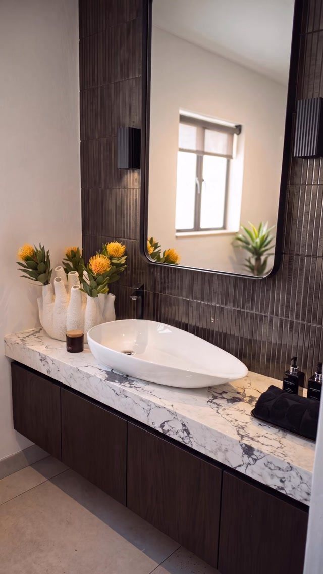 White marble countertop with grey veining featuring a white vessel sink and dark wood cabinets.
