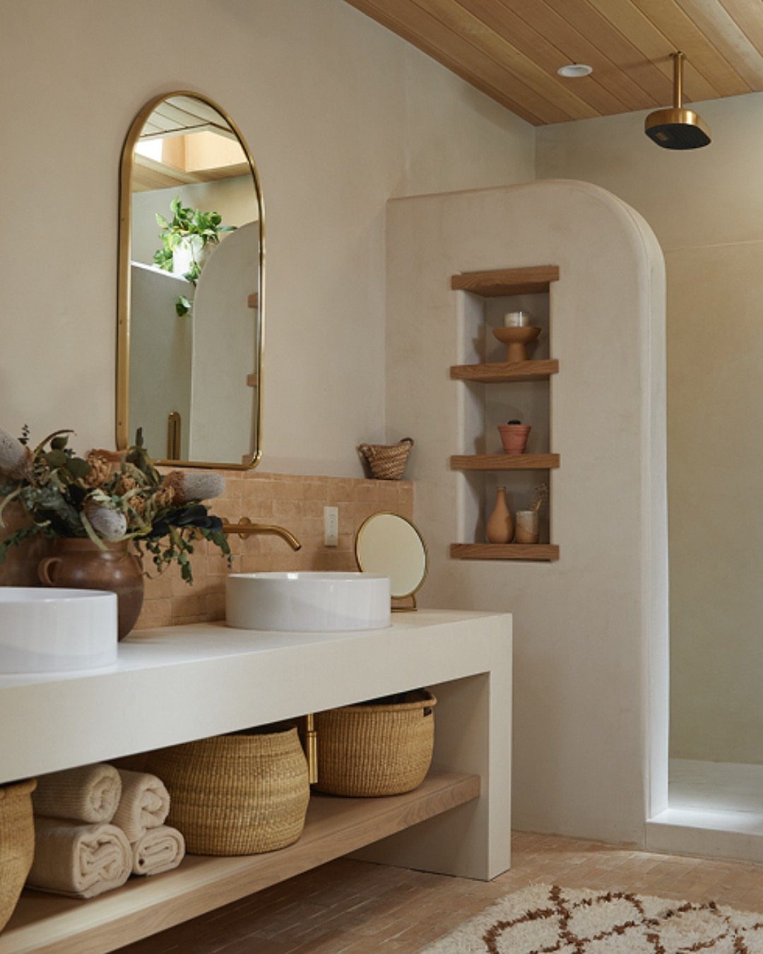 Built-in wooden open shelving recessed into a curved wall next to a modern bathroom vanity.