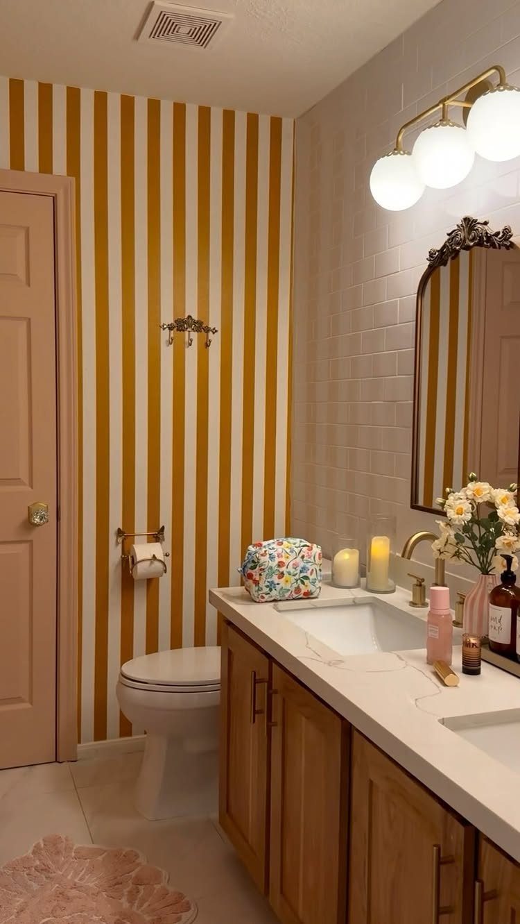Mustard yellow striped wallpaper next to a light pink painted bathroom door and trim.
