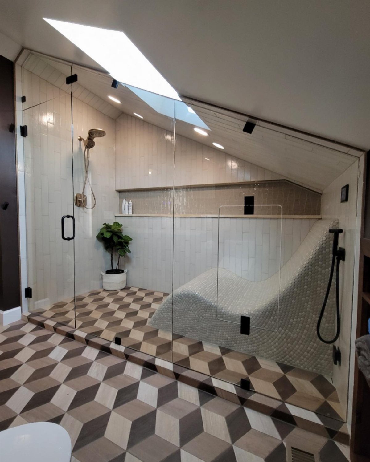 A modern glass-enclosed walk-in shower featuring a built-in tiled lounge seat and skylight.