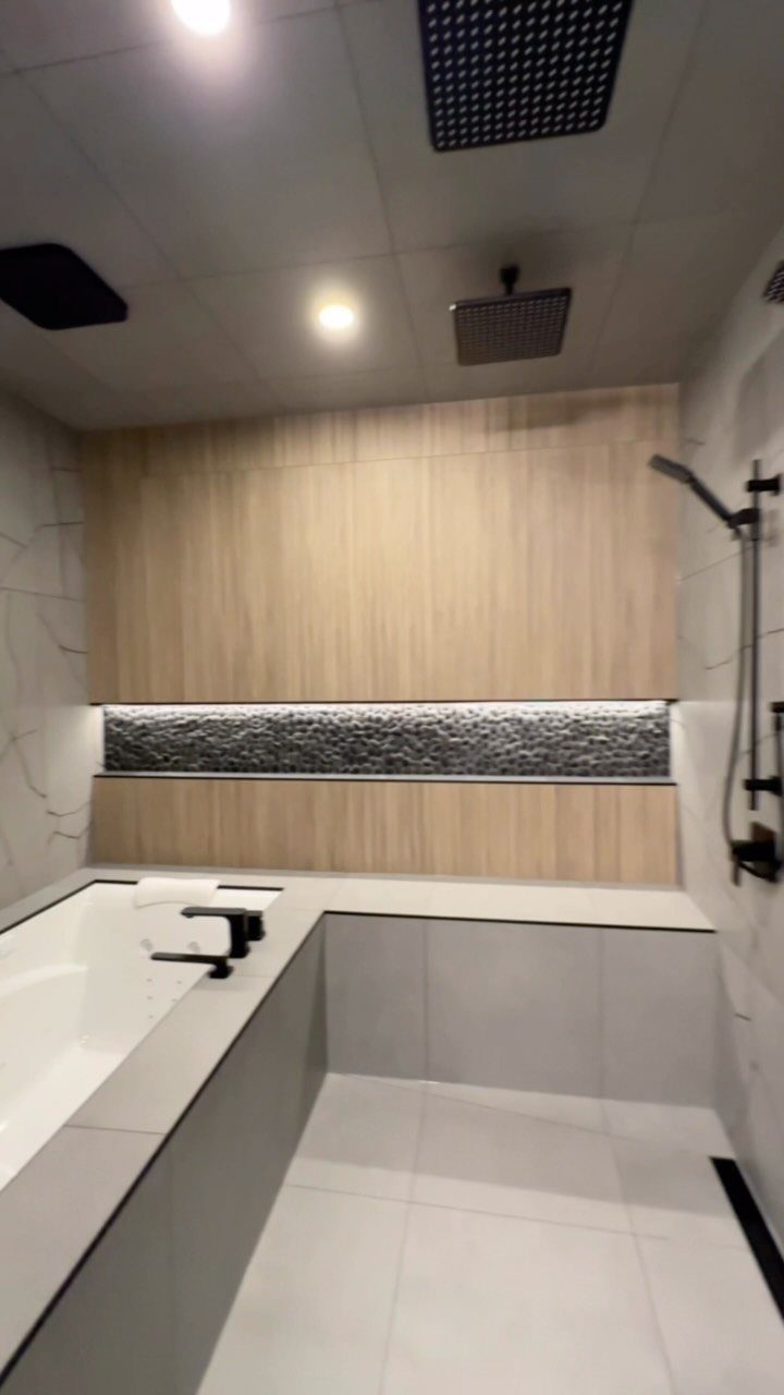 A modern wet room featuring a built-in bathtub and a rainfall shower area.