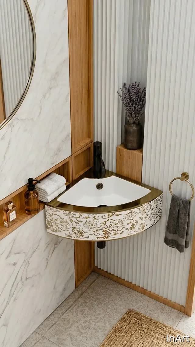 A white corner sink with a decorative gold pattern mounted against fluted white walls.