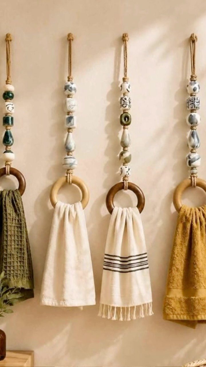Four decorative hanging wooden towel rings with patterned beads holding various colored hand towels.