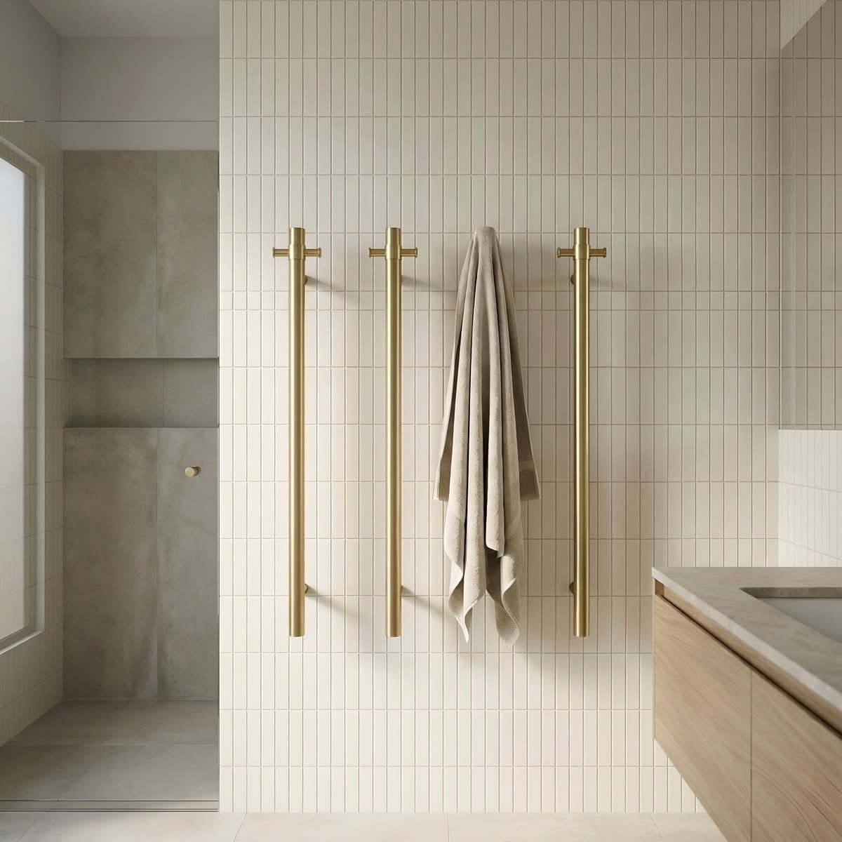 Three vertical gold metal towel bars mounted on a white tiled bathroom wall with one towel hanging.