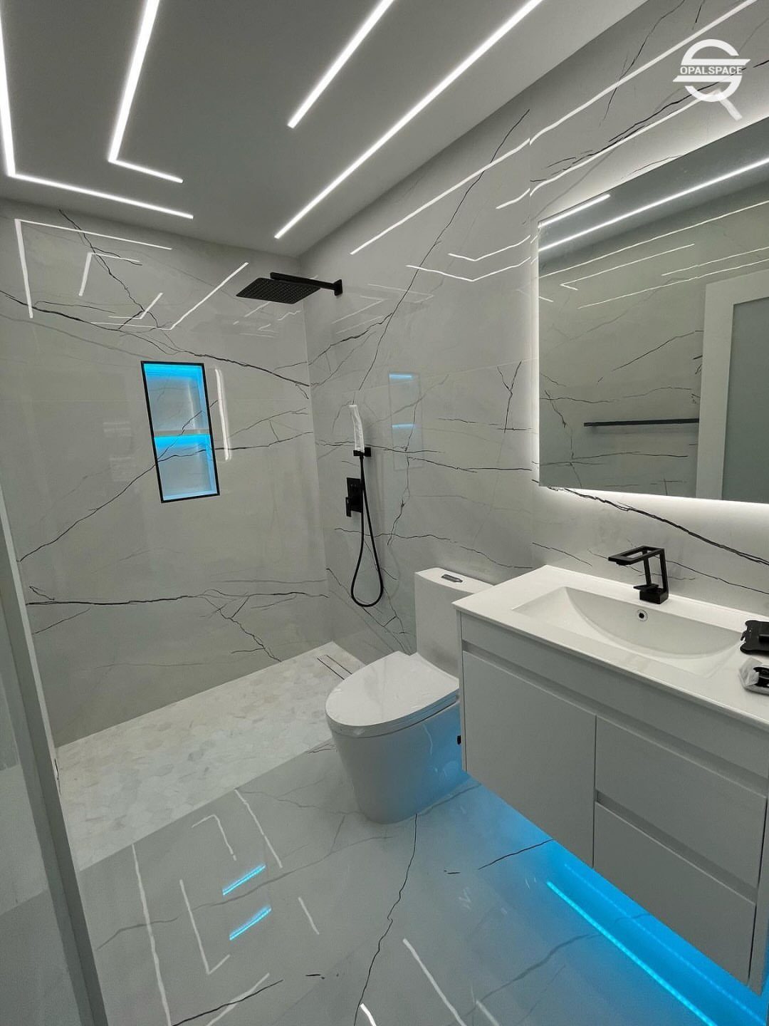 Modern bathroom with marble walls, white vanity, and geometric LED light strips on the ceiling.