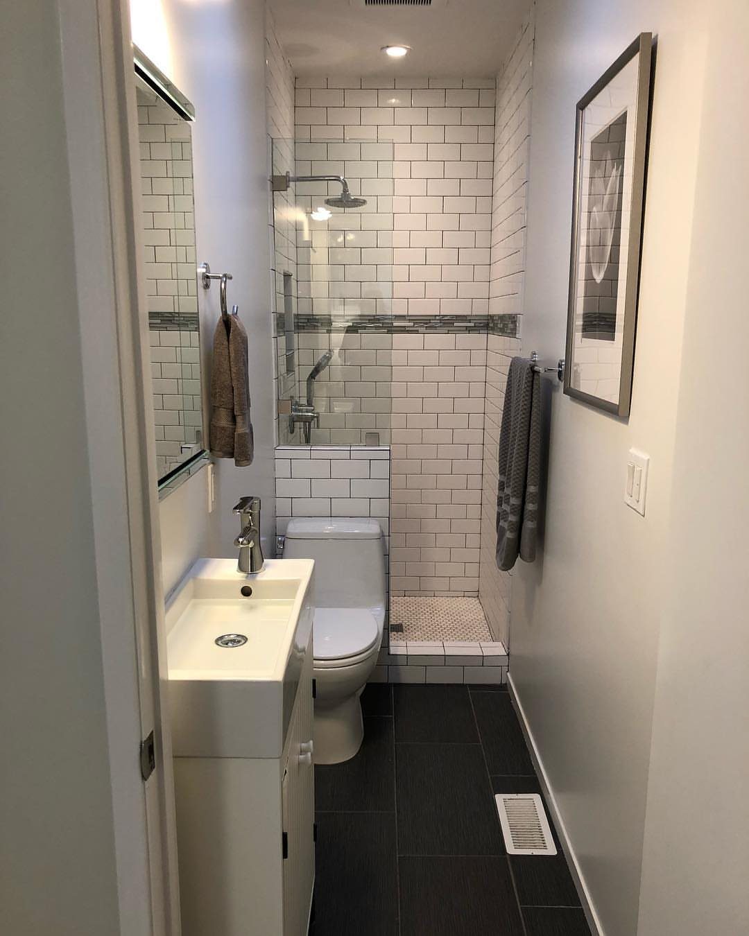A narrow small bathroom with white subway tiles, a toilet, and a compact sink area.