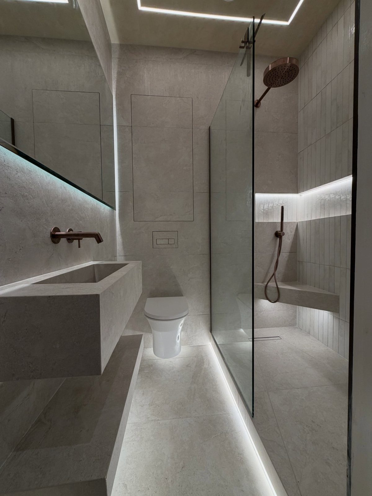 Modern minimalist bathroom with a walk-in shower, floating sink, and integrated LED lighting.