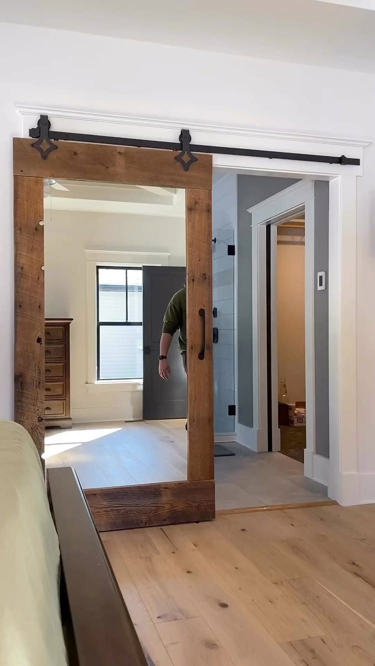 A rustic wooden sliding barn door mounted on a black metal track against a white wall.
