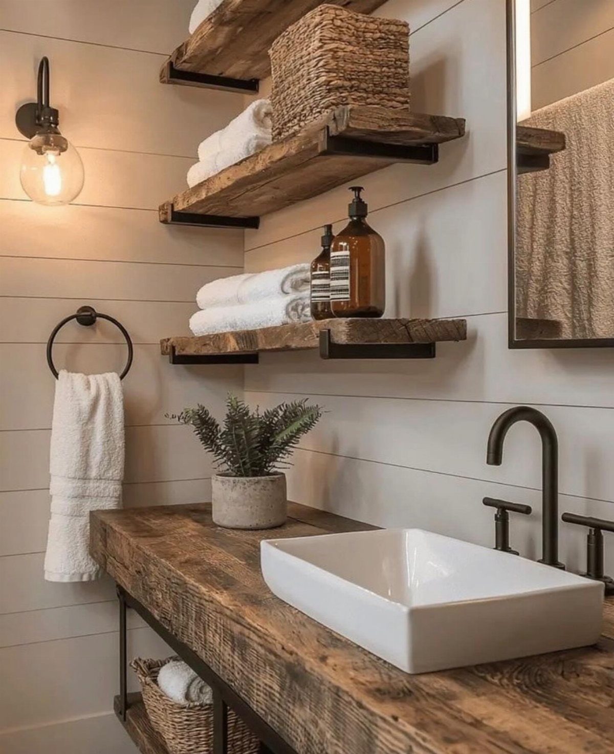 Reclaimed wood vanity and floating shelves in a rustic bathroom with white shiplap walls.