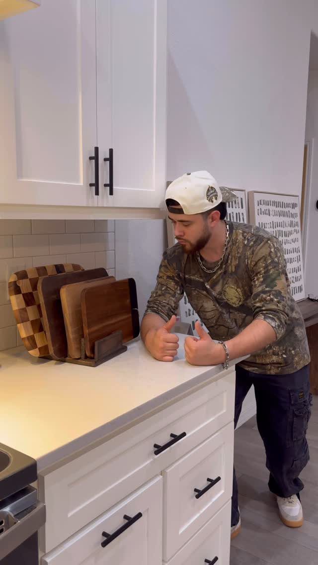 Wooden chopping boards standing upright in a holder on a white kitchen countertop.