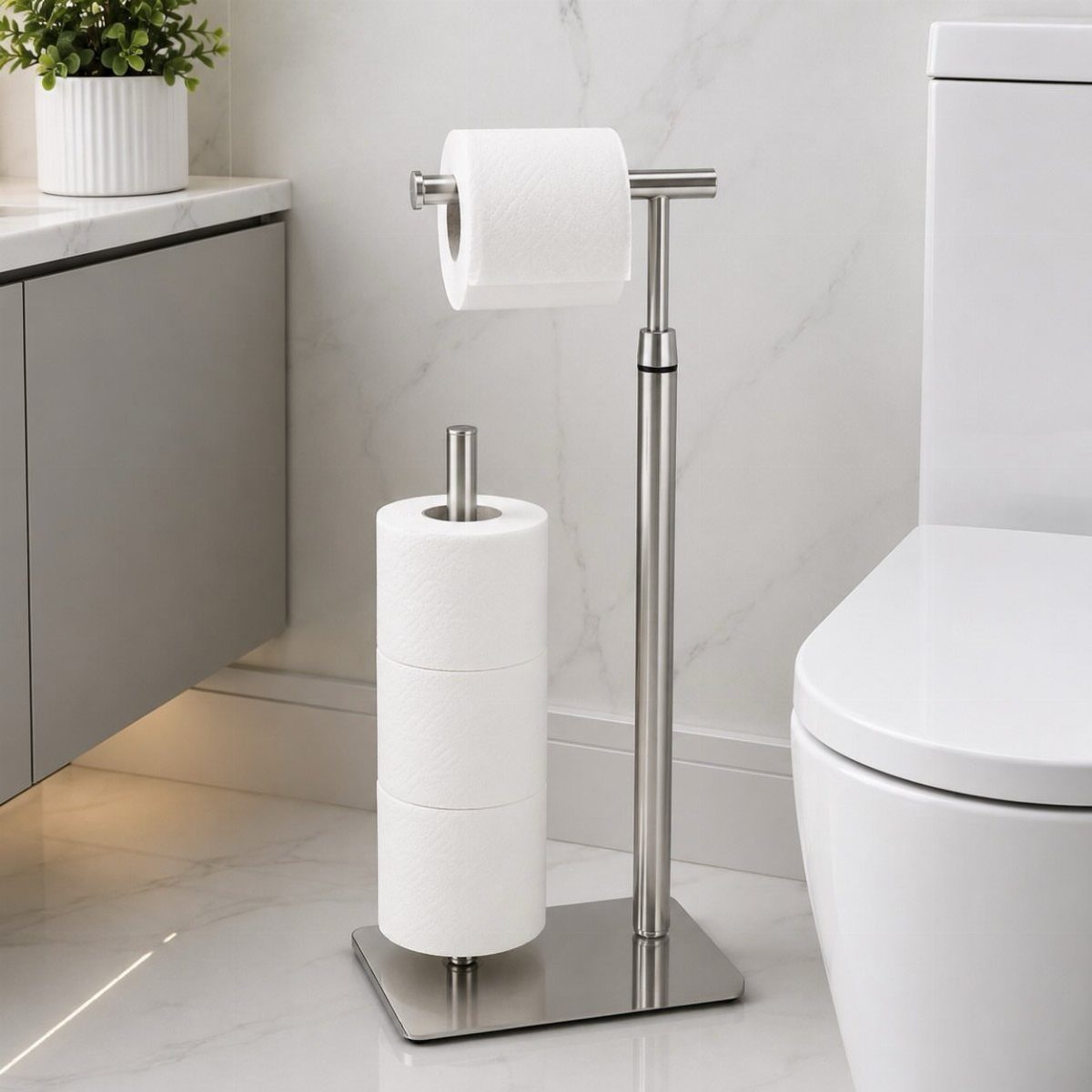 Silver metal freestanding toilet paper holder with multiple rolls next to a white toilet.