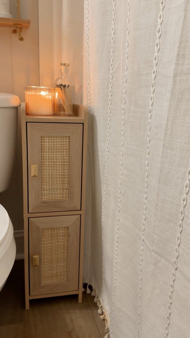 A narrow wooden storage cabinet with cane door panels stands next to a white toilet.