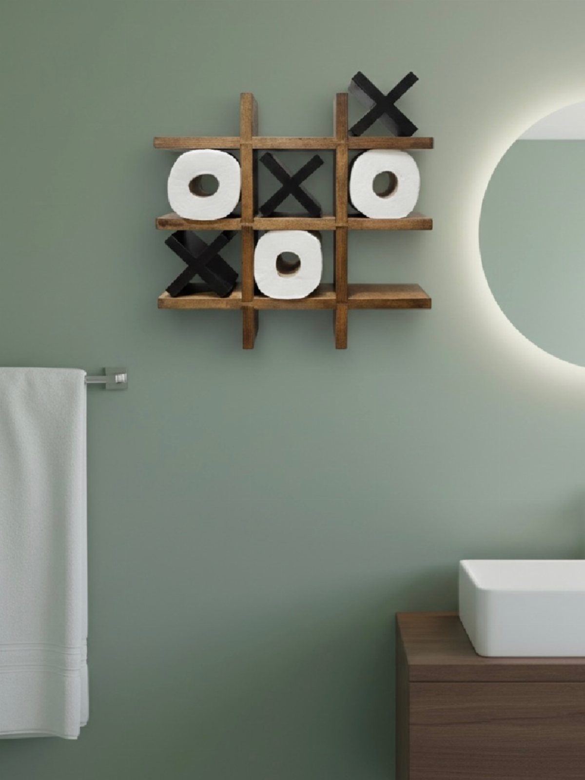 Wooden Tic Tac Toe wall shelf holding white toilet paper rolls on a green bathroom wall.