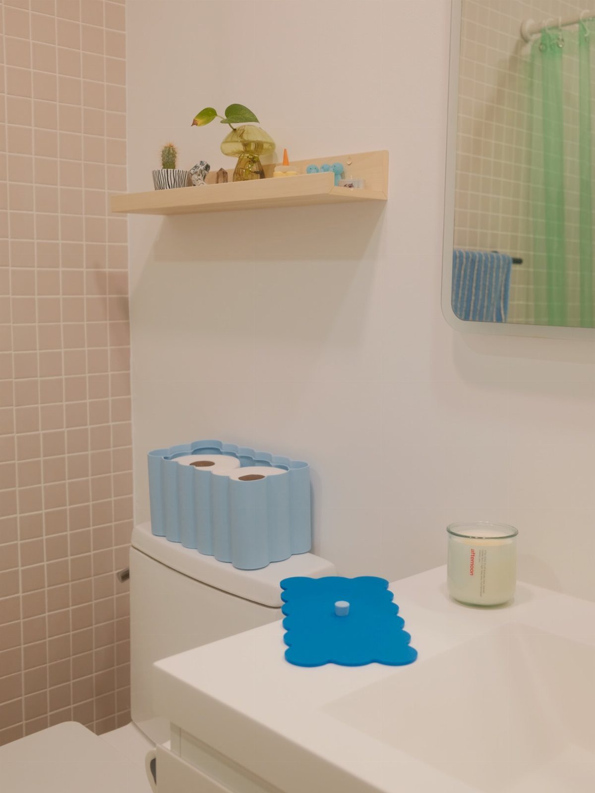 Blue corrugated toilet paper holder sitting on a white toilet tank in a bathroom.