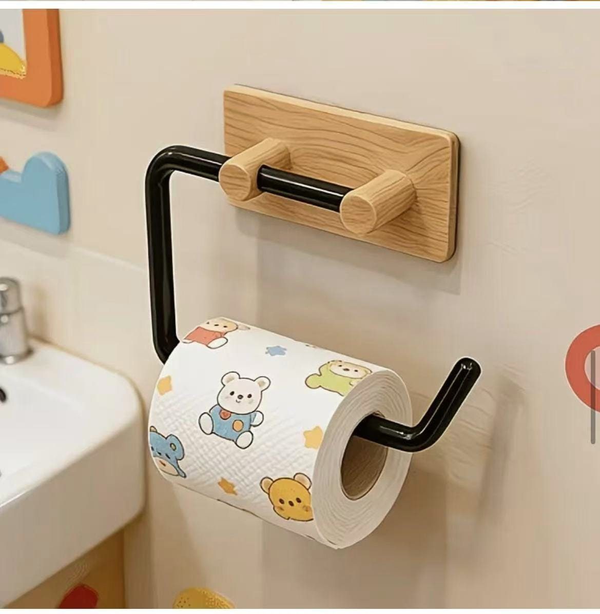 A wooden wall-mounted toilet paper holder with a black metal rod holding patterned paper.