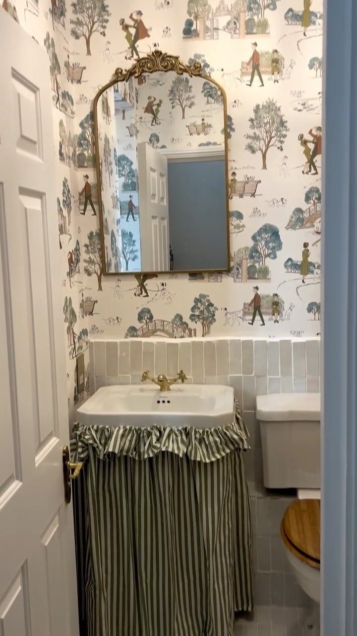 A white pedestal sink decorated with a green and white striped fabric sink skirt.