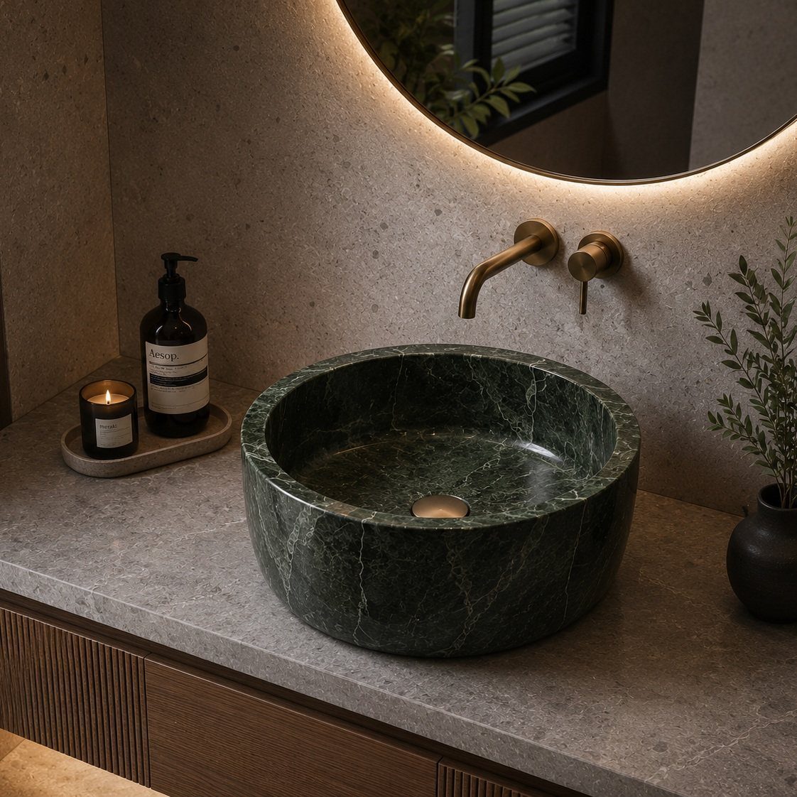 A dark green marble vessel sink on a gray stone bathroom countertop with gold fixtures.