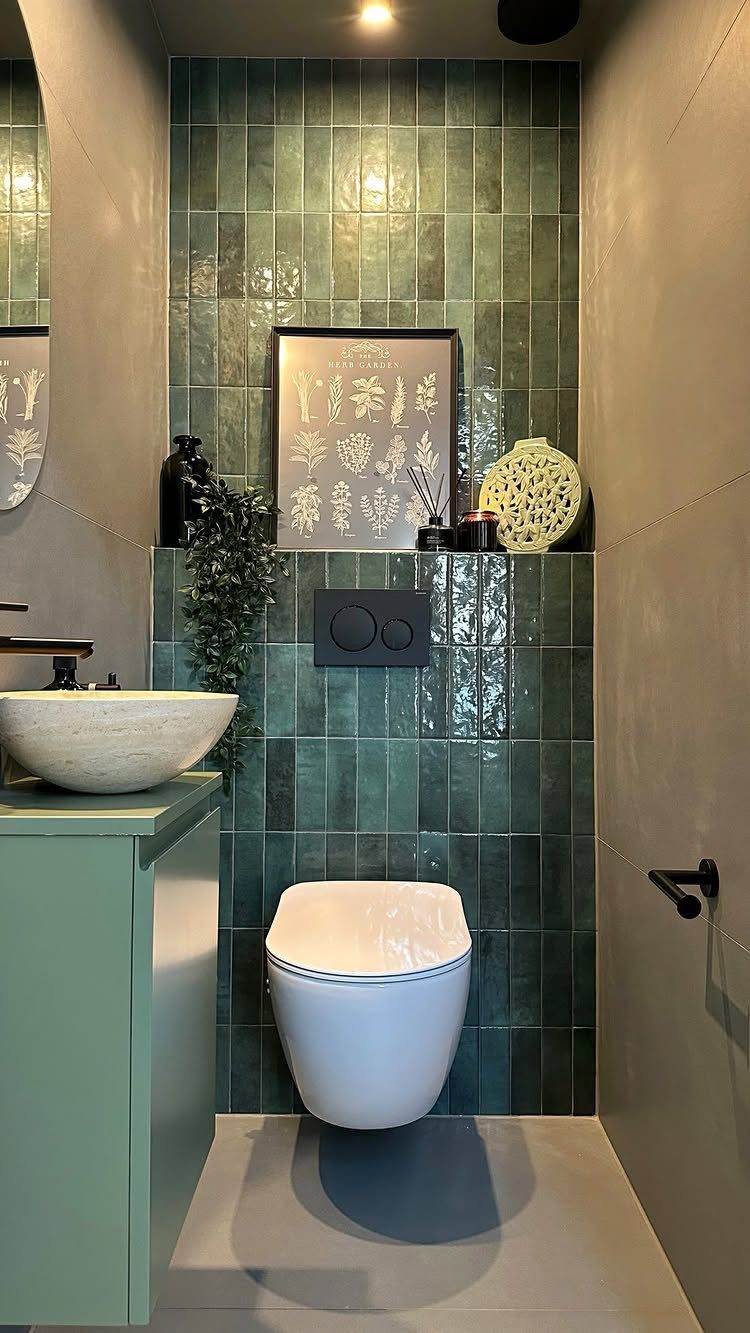 Green tiled bathroom wall with a stone vessel sink on a light green vanity.