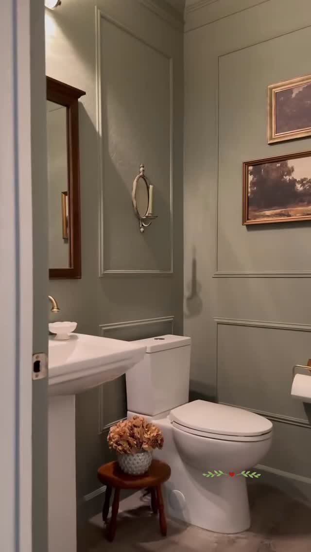 Sage green bathroom walls with decorative molding, a white pedestal sink, and a toilet.