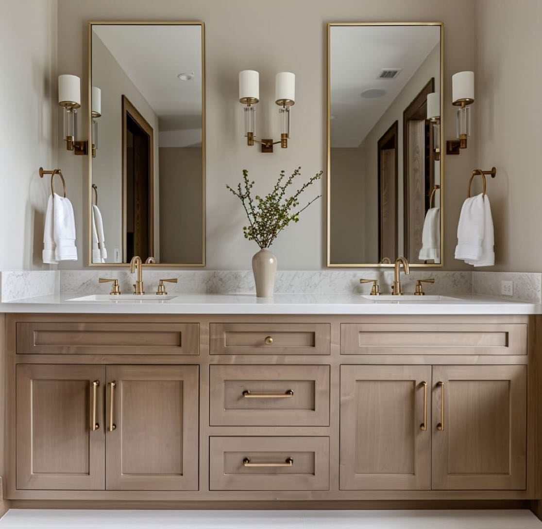 A light wood double sink vanity with gold hardware and two tall rectangular mirrors.
