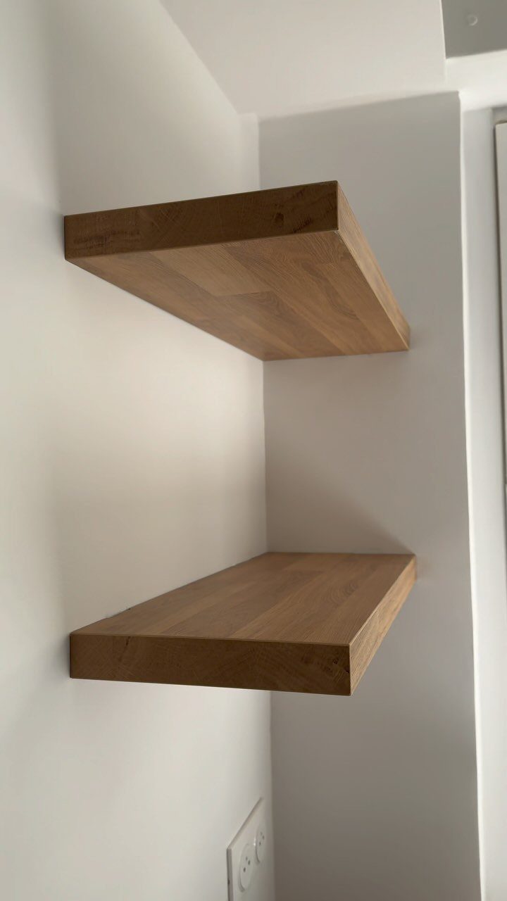Two thick wooden floating shelves mounted on a white wall in a corner.