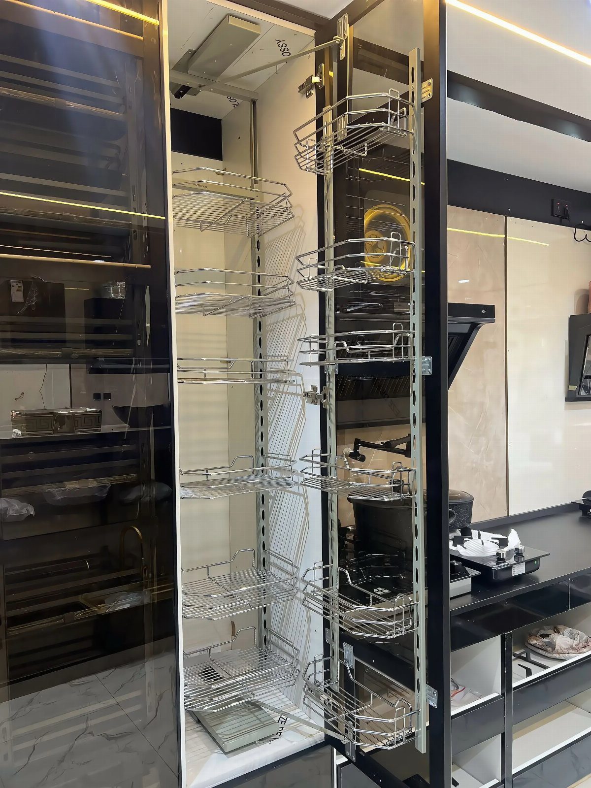 A tall chrome wire pull-out pantry shelving unit extended in a modern kitchen cabinet.