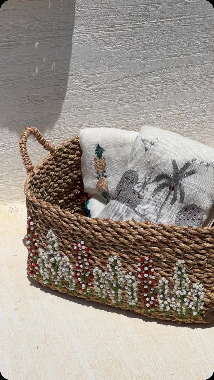 A woven decorative basket with colorful beadwork containing folded white patterned towels.