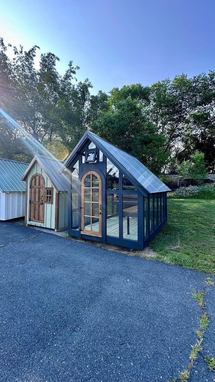Two small wooden garden sheds, one light green and one dark blue with large glass windows.