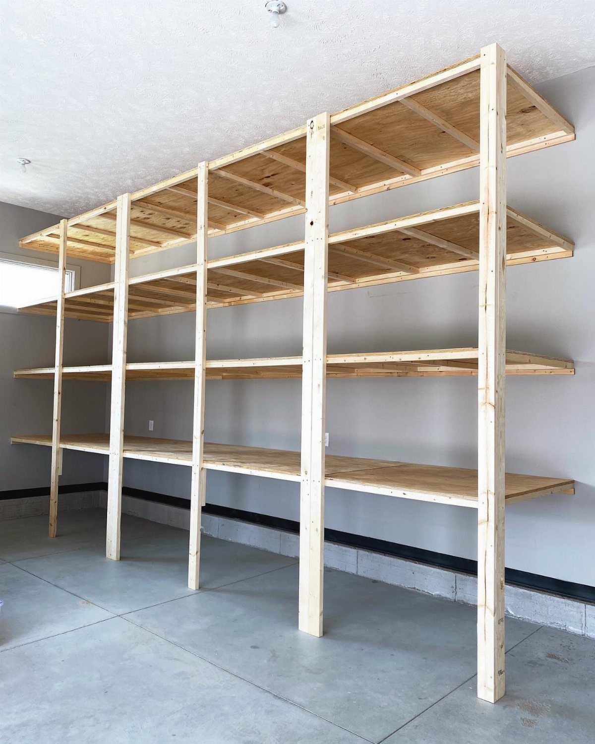 Large wooden multi-tier shelving unit standing against a grey wall in a garage.