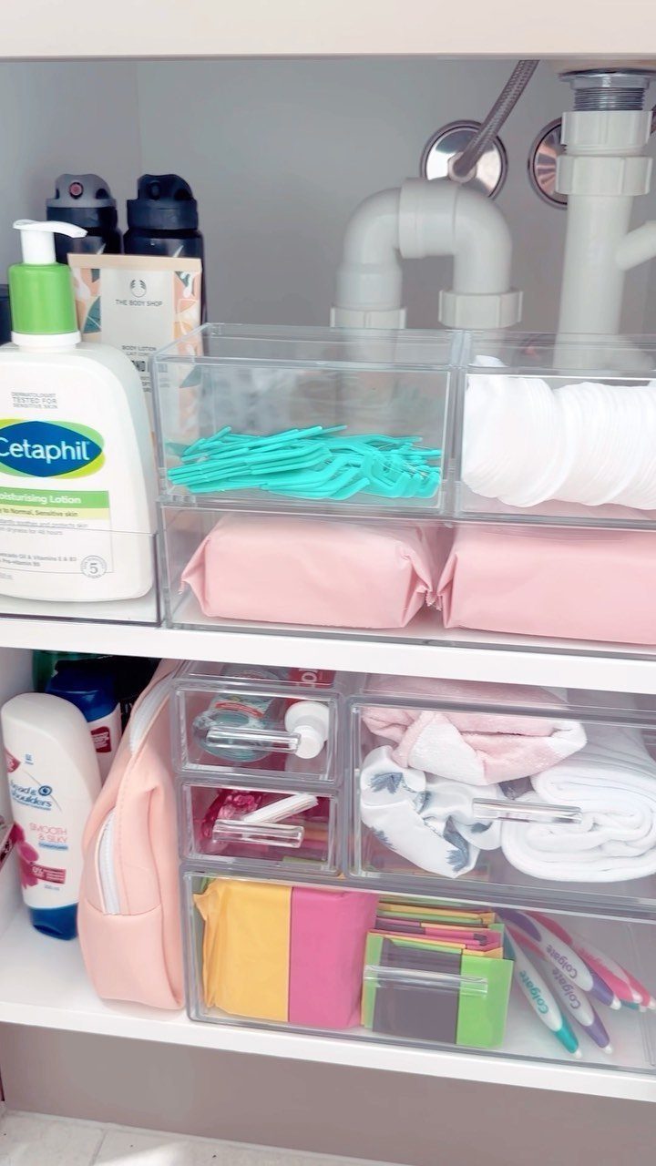 Clear plastic organizers filled with various toiletries and skincare products inside a white bathroom cabinet.