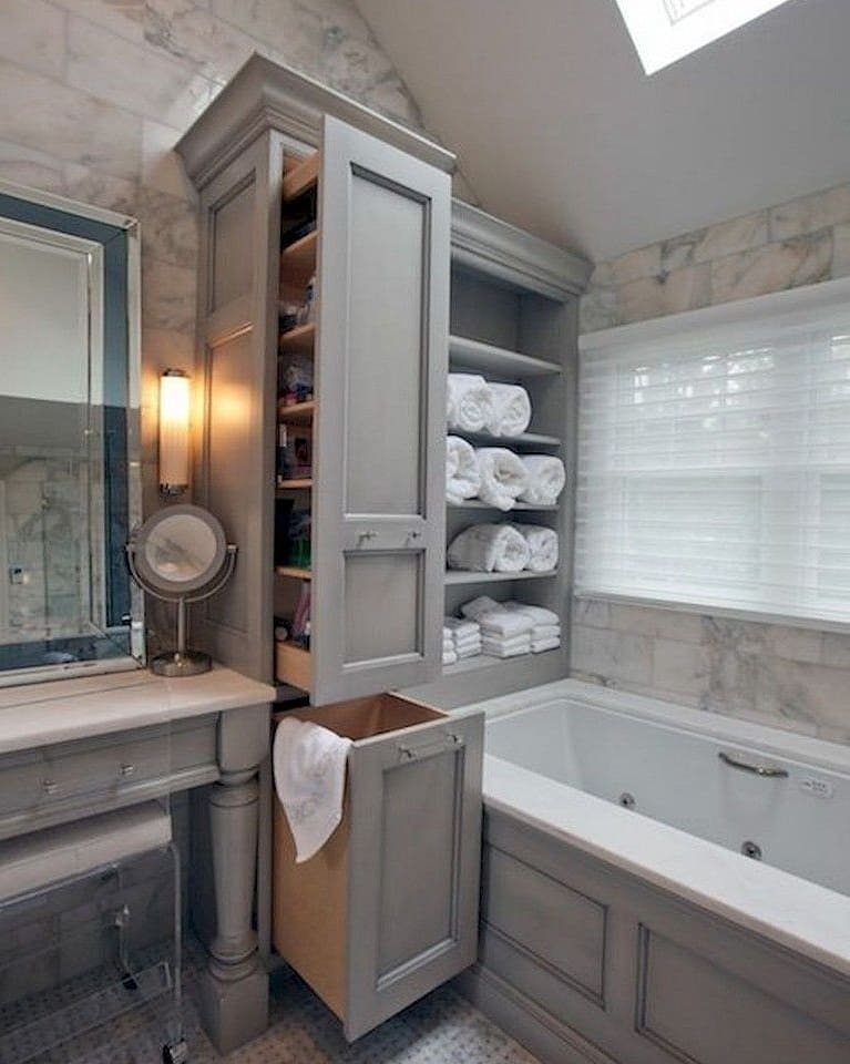 Grey built-in bathroom cabinetry with open shelves holding rolled white towels and closed storage compartments.