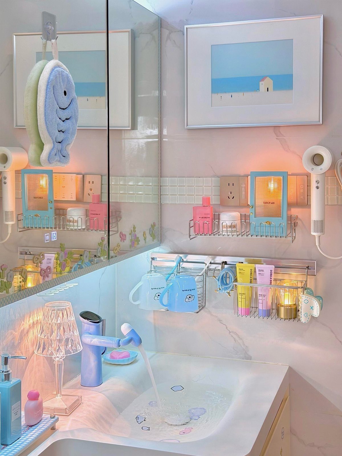 A small bathroom with light pink marble walls and pastel blue accessories near a white sink.