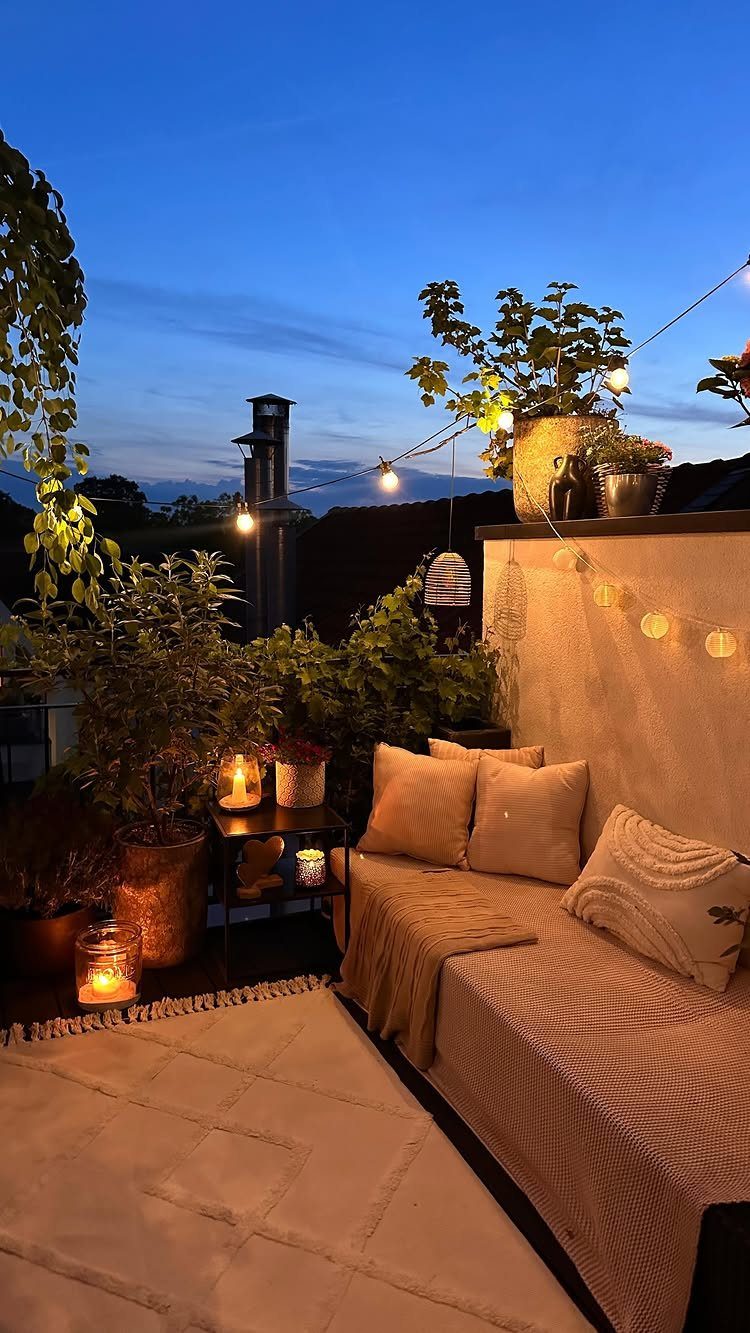 Potted plants and cozy outdoor seating with string lights on a small patio at dusk.