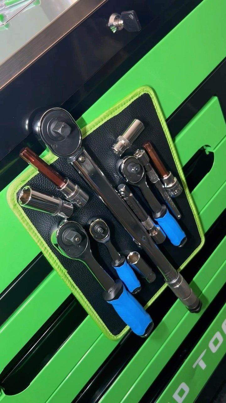 Silver metal socket wrenches and sockets attached to a black and green magnetic tool holder.