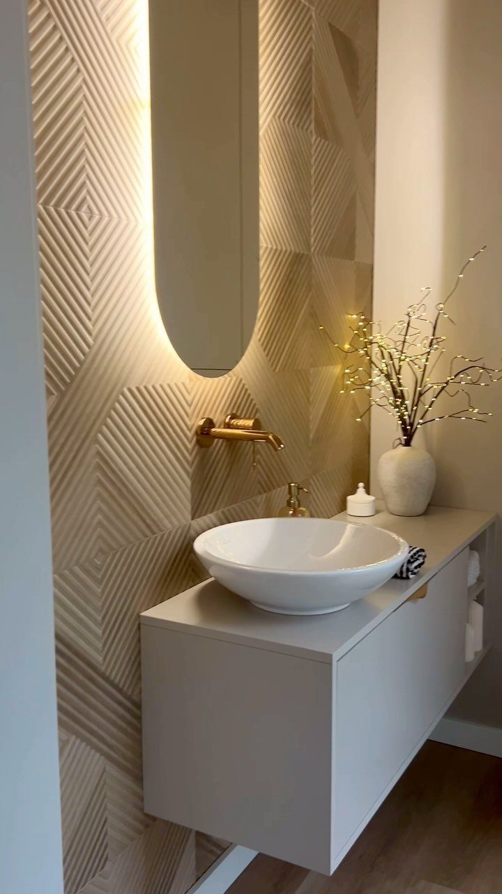 A modern bathroom vanity with a white vessel sink and textured geometric wall tiles.
