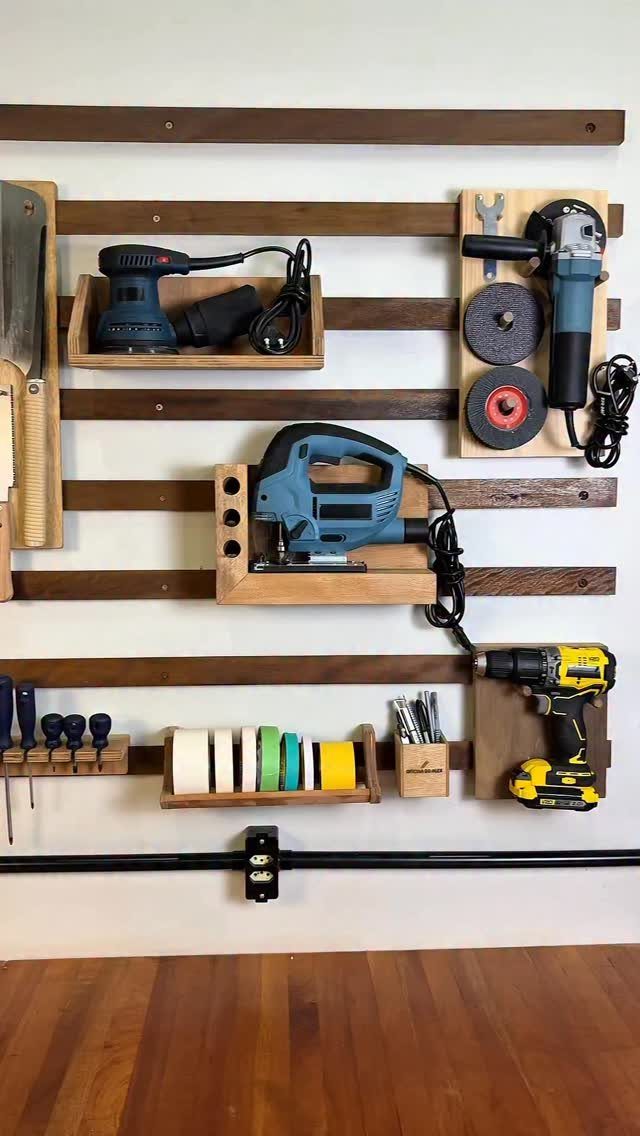 Power tools organized on a wooden slat wall storage system with custom holders.