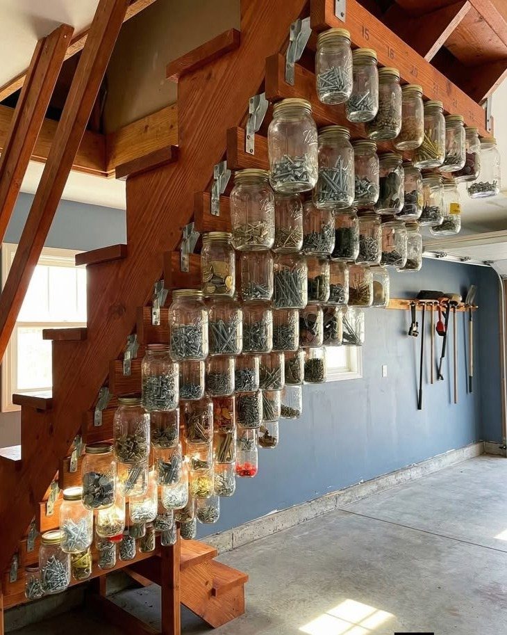 Glass mason jars filled with hardware mounted to the side of a wooden staircase.