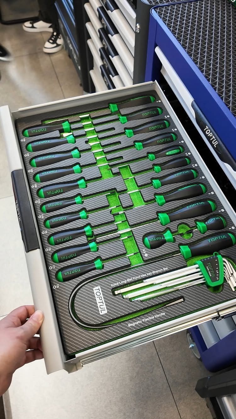 An open tool chest drawer containing organized screwdrivers in green foam inserts.