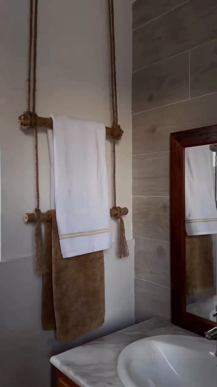 Wooden rods suspended by ropes hanging on a wall with white and brown towels.