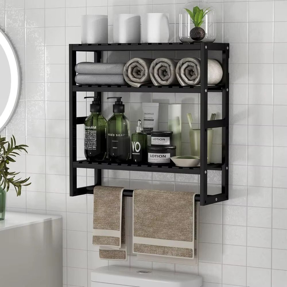 Black metal multi-tiered bathroom shelf unit holding towels and toiletries on a white tiled wall.