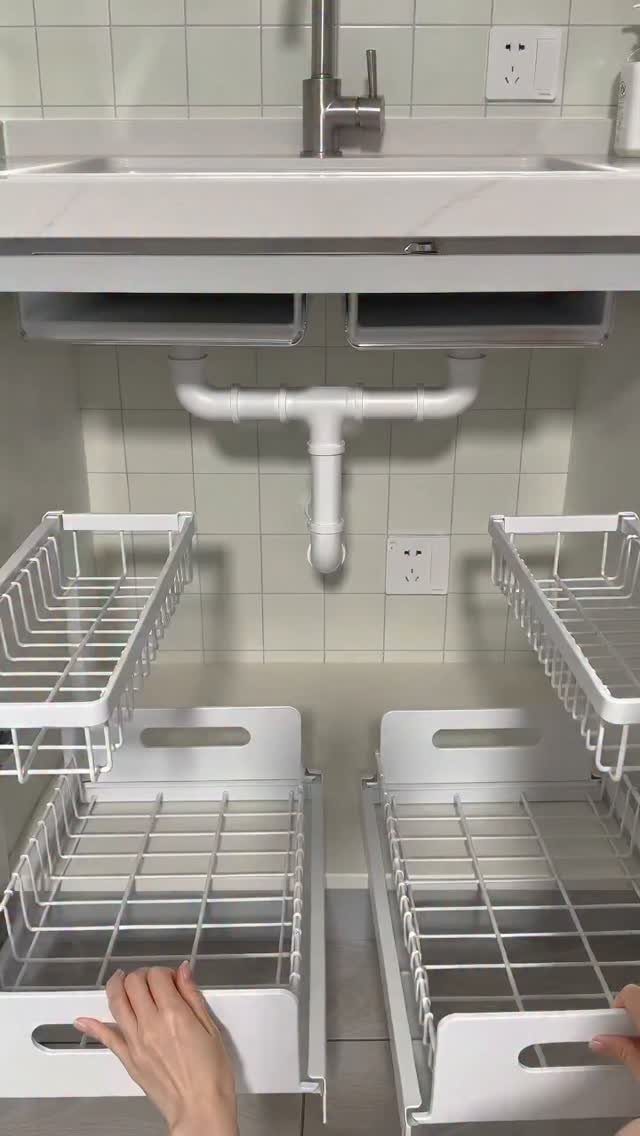 White wire pull-out baskets and sliding storage units installed under a white bathroom sink.