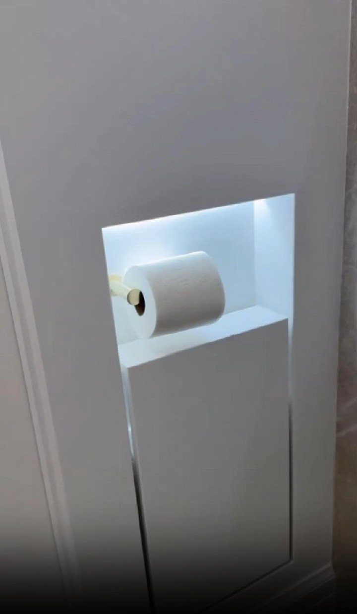 A roll of white toilet paper sitting inside a glowing, recessed wall niche.