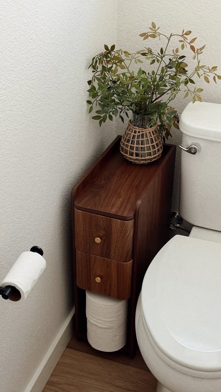 Dark wood slim storage cabinet with two drawers placed between a toilet and a wall.