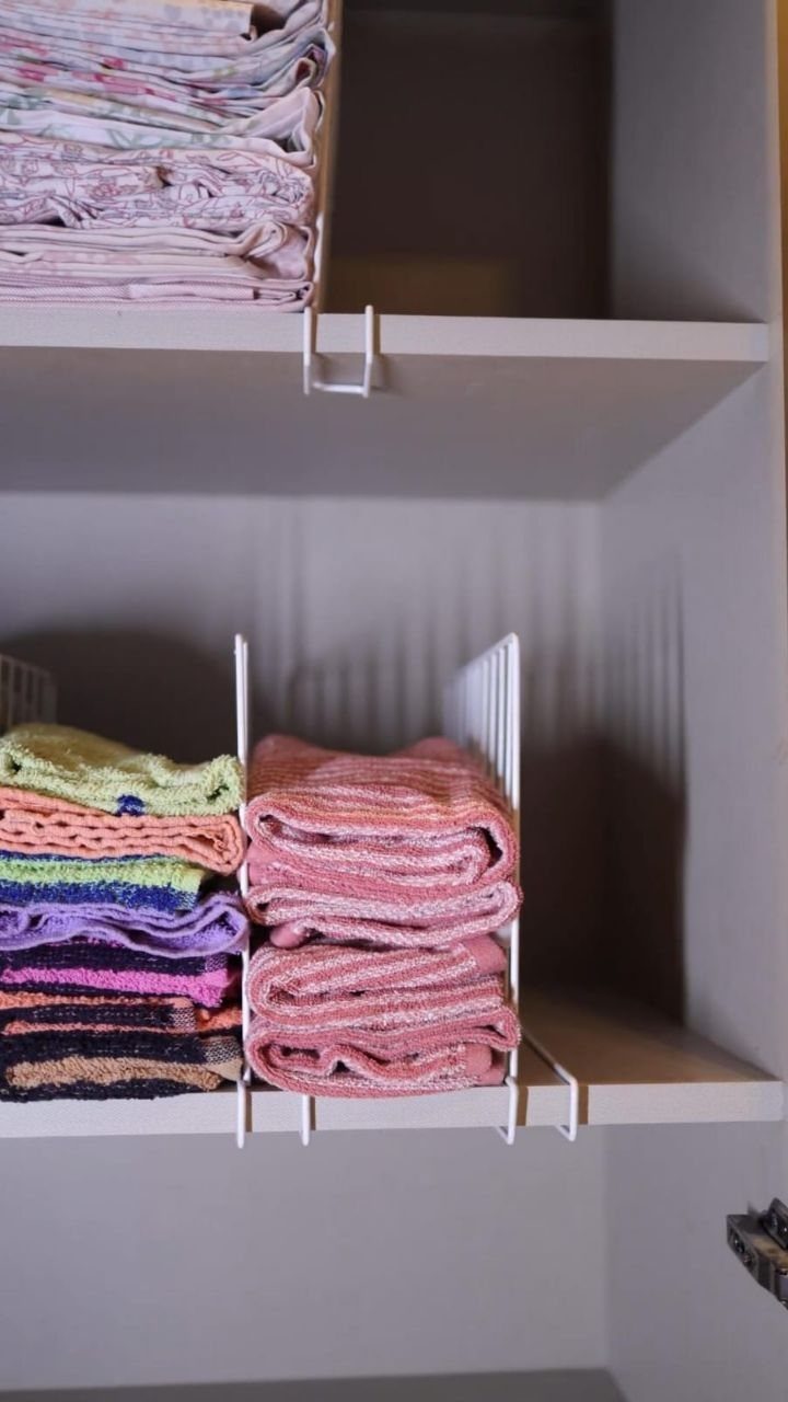 White wire shelf dividers holding stacks of neatly folded colorful towels on white shelves.