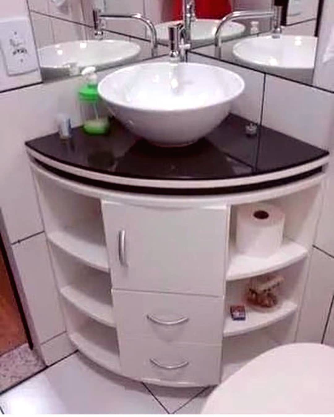 White corner bathroom vanity with a black countertop and a white vessel sink.