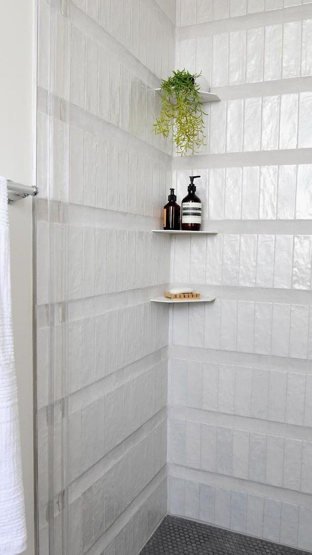 White handcrafted rectangular tiles with a glossy texture installed on a bathroom wall.